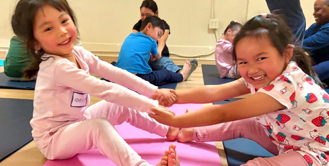 Two kids laughing together on yoga mats